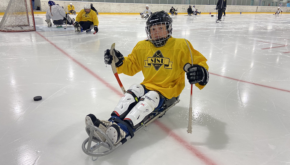 Nuori jääkiekkoilija istuu jääkiekkokelkassa