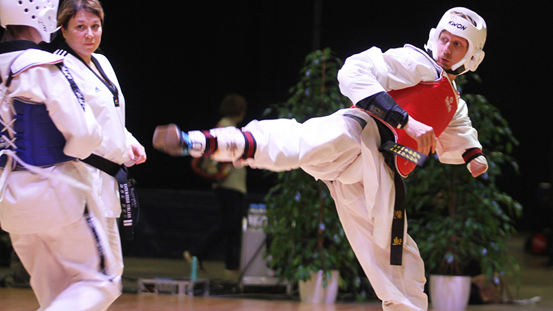 Matti Sairainen nostamassa jalkaansa potkuun parataekwondon kilpatatamilla.