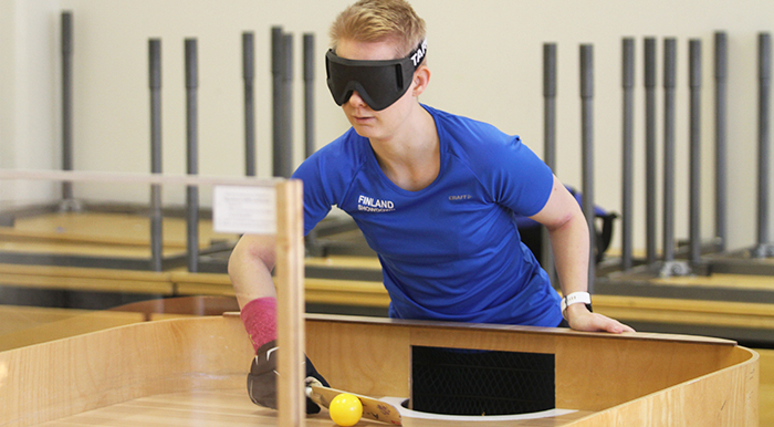 Hanna Vilmi sokkopingiskilpailussa lyömässä palloa maalinsa edestä läpinäkymättömät pelilasit silmillään.